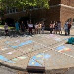 Students Pose with Chalk Designs on a Storm Drain from Forest Park Elementary
